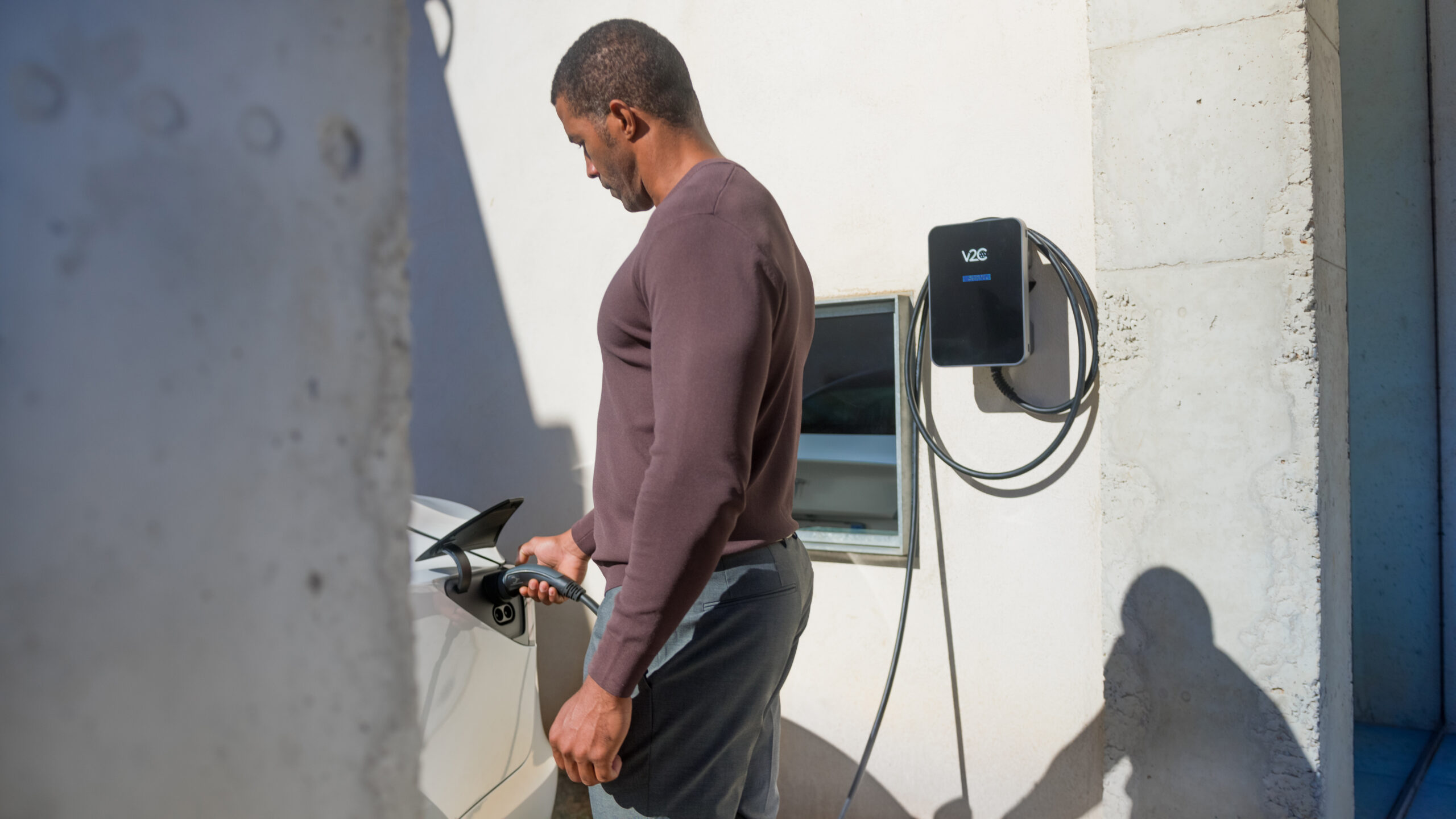 Uomo che collega l'auto elettrica alla wallbox V2C Trydan installata a casa