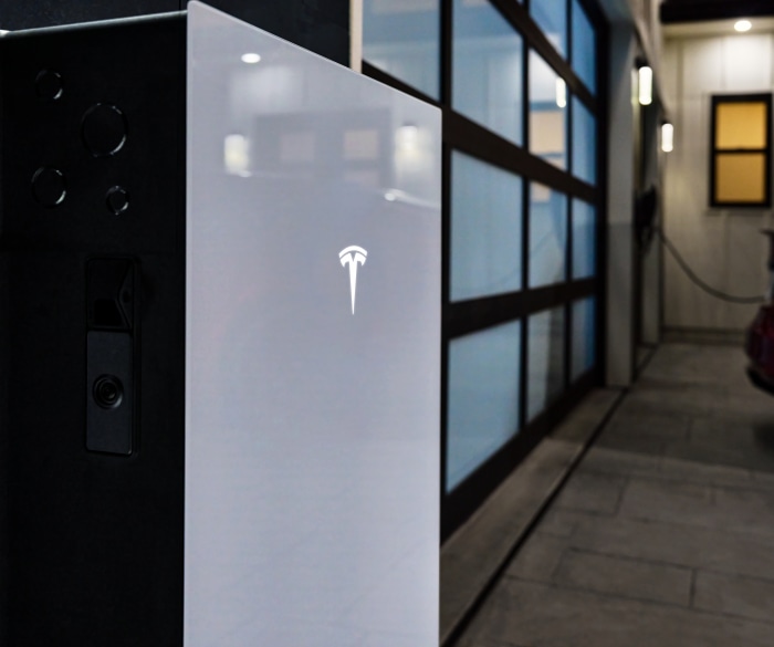 Tesla Powerwall installato a parete, con logo Tesla illuminato